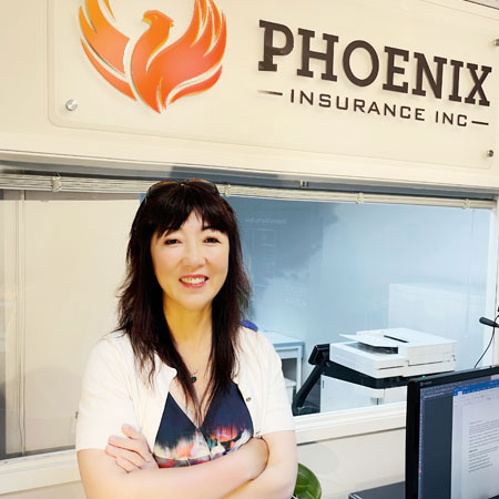 A photo of Phoenix Insurance founder and President, Grace Zheng standing in front of a company logo.